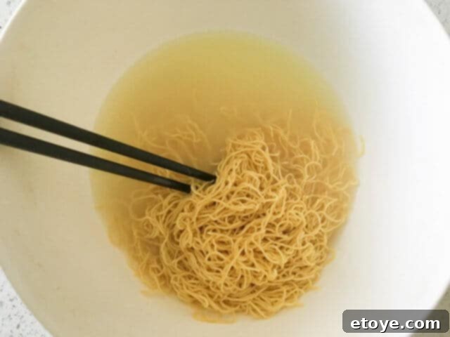 Hot water being poured over fresh Chinese noodles to quickly heat them.