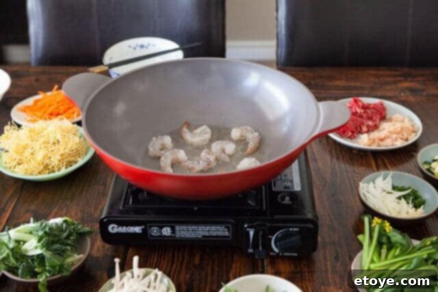 Shrimp searing in a hot wok, showing ample space for browning without overcrowding.