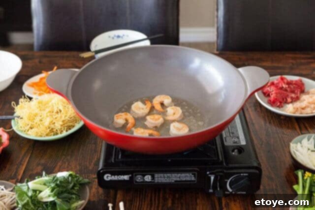 Shrimp being flipped in a wok to brown on the second side during the stir-fry process.