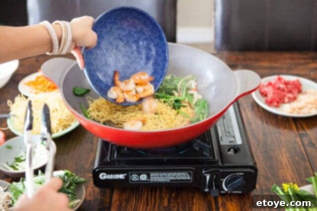 Half-cooked shrimp added back into the wok with noodles and vegetables to finish cooking.