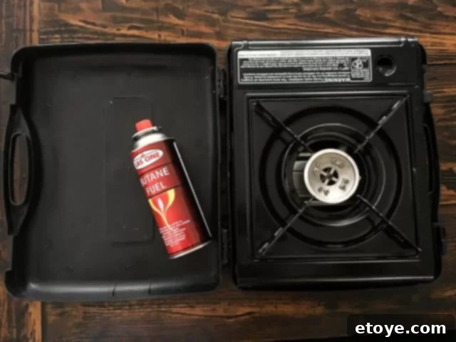 A portable butane stove set up on a dining table, ready for interactive Mongolian BBQ cooking.