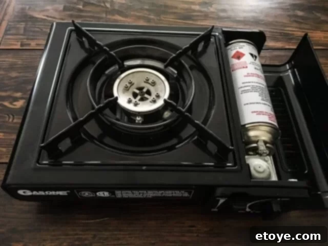 Close-up of a hand inserting a butane canister into a portable stove, highlighting the ease of setup.