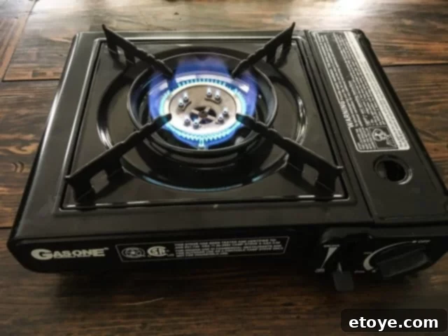 Another view of a butane canister being locked into place on a portable stove, ready for cooking.