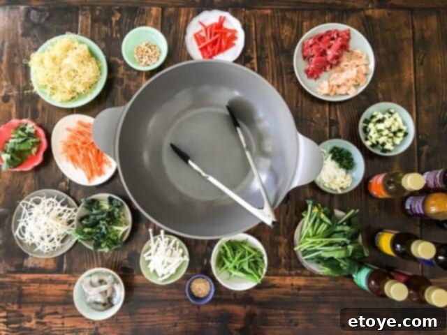 A well-organized tabletop setup for DIY Mongolian BBQ, featuring a portable stove, wok, and various ingredient bowls.