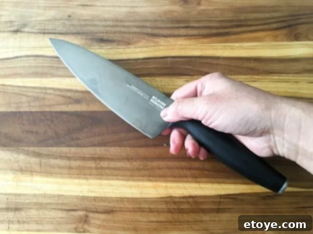 A person expertly slicing vegetables with a Kuhn Rikon Colori Titanium knife, demonstrating its ease of use.
