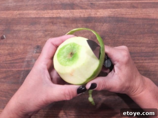 A Kuhn Rikon Colori Titanium paring knife in action, peeling an apple with precision.