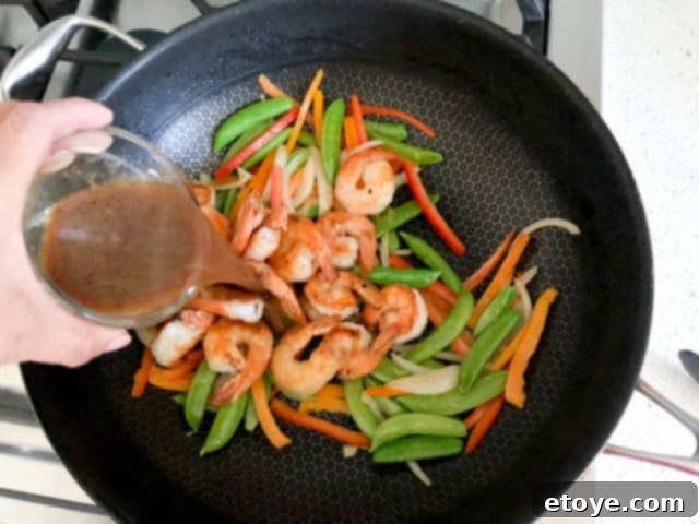 Shrimp Teriyaki Recipe stir fry vegetables Shrimp Teriyaki Recipe pouring homemade teriyaki sauce over the stir fry
