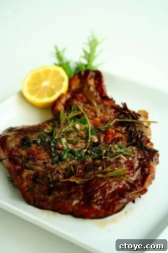 A perfectly cooked grilled ribeye steak, infused with garlic and rosemary, served elegantly on a white plate