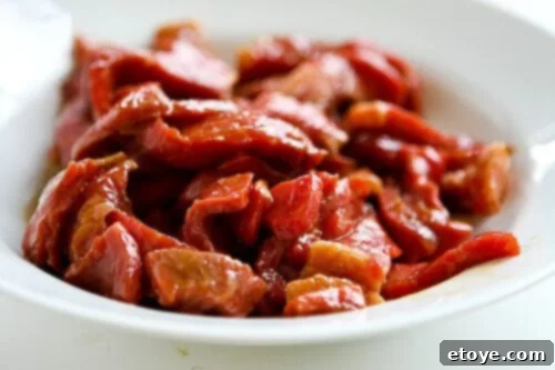 Thinly sliced beef sirloin marinating in a bowl with soy sauce, cornstarch, sugar, oyster sauce, and rice wine