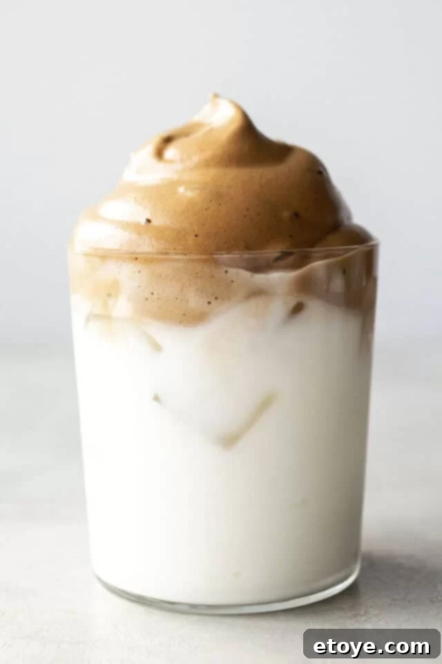 A glass of Dalgona Coffee with frothy whipped topping.