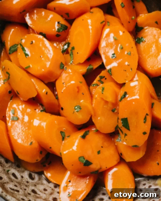 A bowl of microwaved steamed carrots with butter, herbs, and seasonings, on a wooden surface.