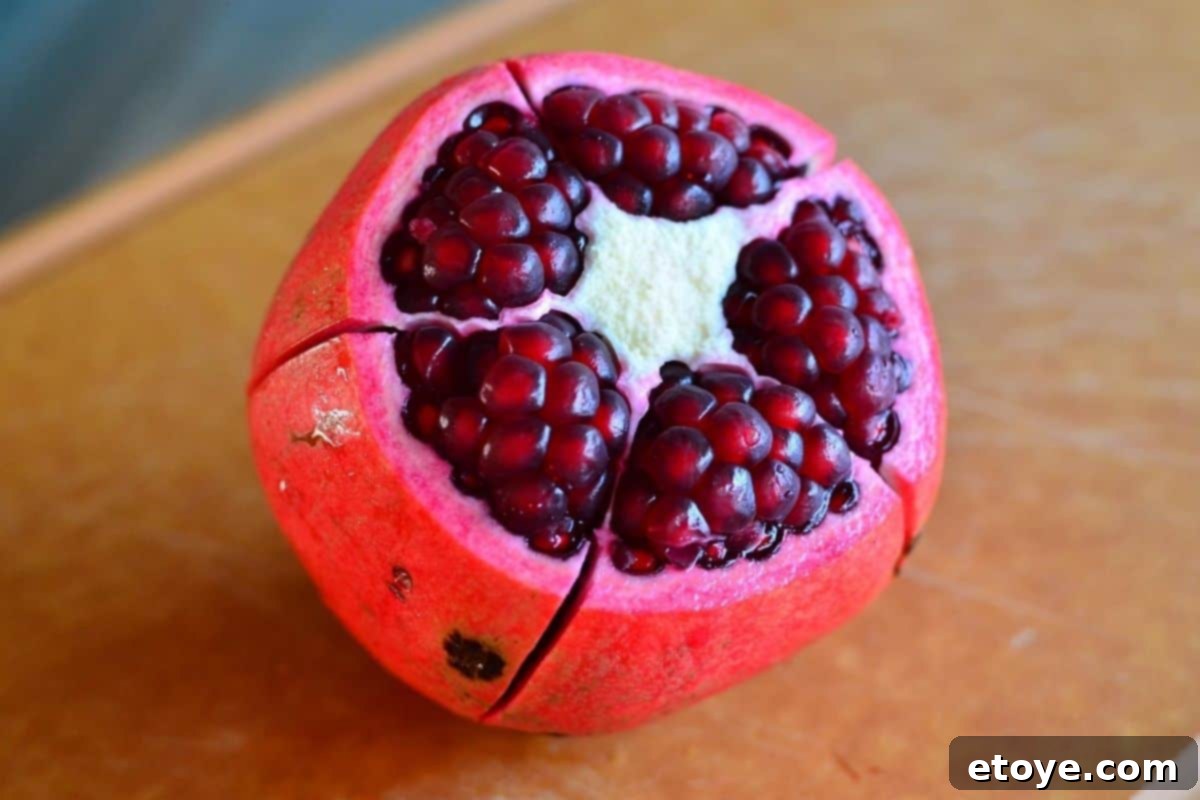 A vibrant, artfully arranged Buddha Bowl topped generously with fresh pomegranate seeds and various chopped nuts, presented ready for serving.