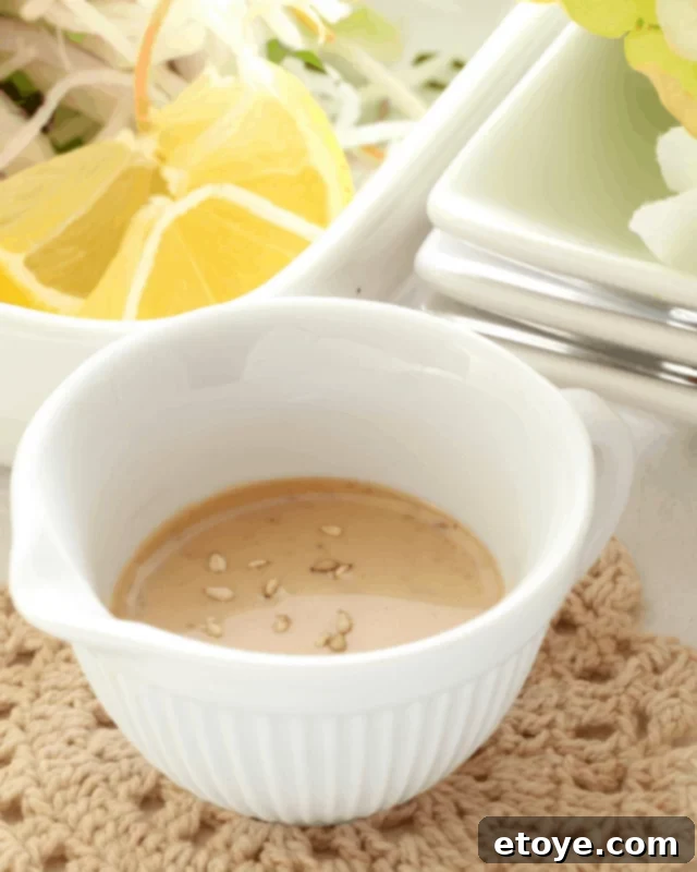 A crisp, green salad generously drizzled with the homemade roasted sesame dressing, highlighting its creamy texture and appetizing appeal.