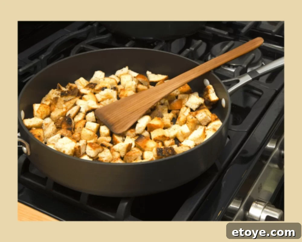 Crispy Homemade Croutons 4 Cooking homemade croutons on a stovetop in a large pan, showing them browning.