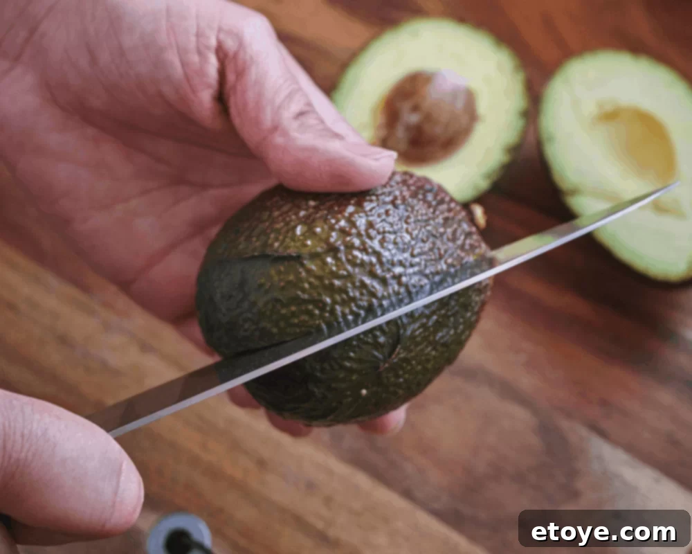 Avocado Slicing Made Simple 4 Chef's knife slicing lengthwise around an avocado pit
