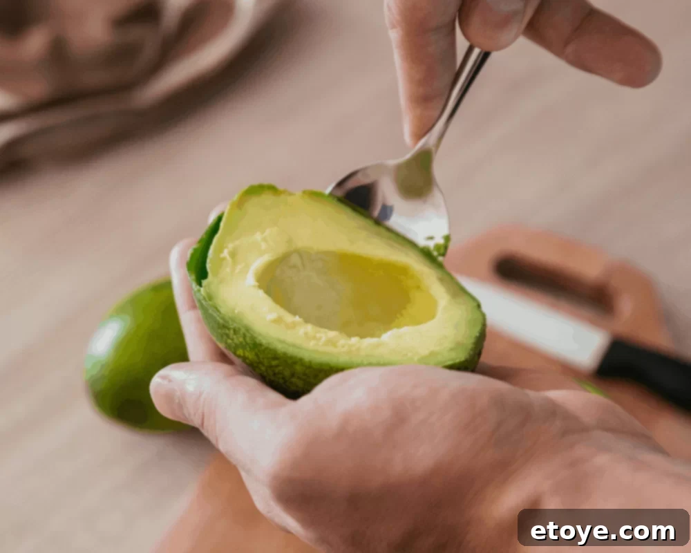Avocado Slicing Made Simple 6 Large spoon scooping out avocado flesh from the skin