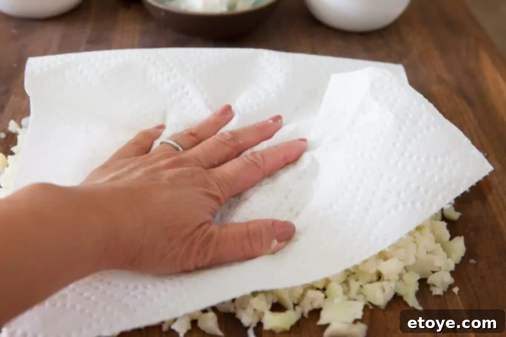 Patting cauliflower rice dry with paper towels before cooking