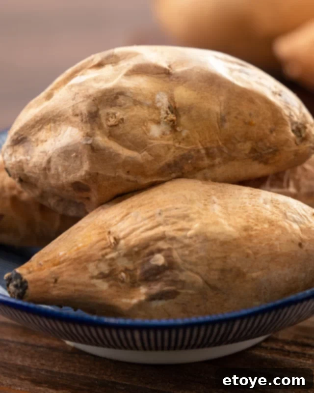 Two cooked sweet potatoes in a blue bowl, garnished with fresh herbs.