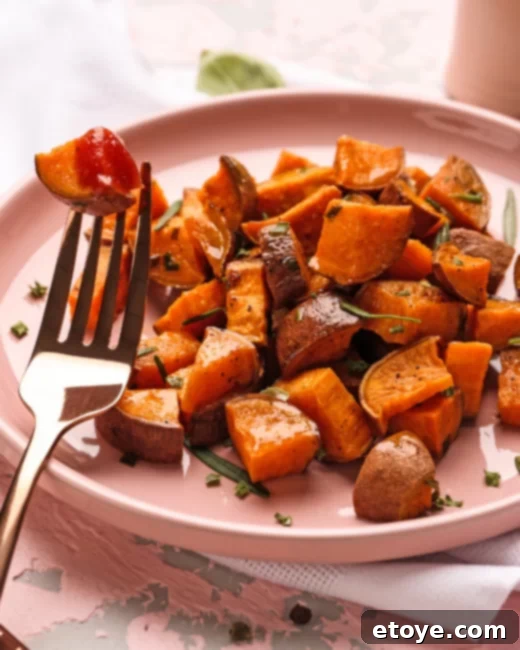 Diced sweet potatoes on a pink plate, garnished with fresh herbs, showcasing a delicious serving suggestion.
