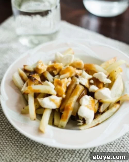 Creative Uses for Leftover Latkes 6 Delicious poutine made with golden-brown french fries, generous cheese curds, and rich brown gravy, served on a classic white plate.