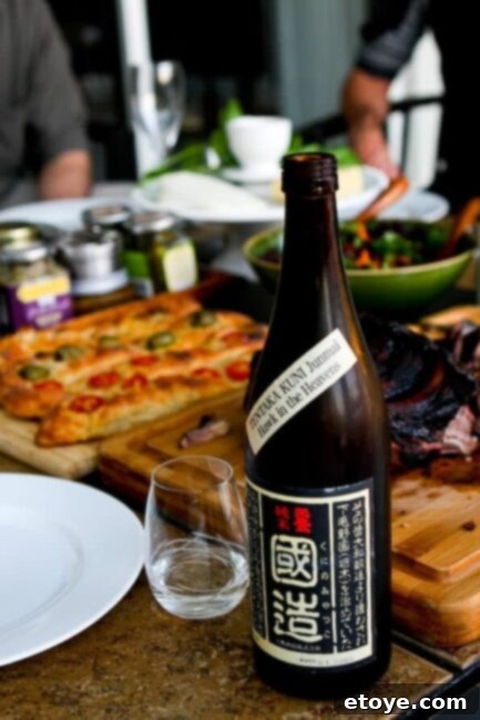 Close-up of a sake glass next to a cheese board with bread, demonstrating a non-Japanese pairing. A close-up of sake and food, featuring cheese and bread