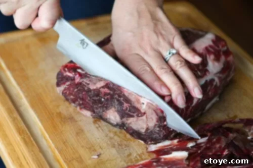Carefully trimming the hardened pellicle from the dry-aged beef