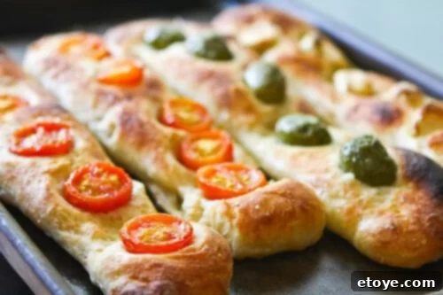 Freshly baked Jim Lahey's No-Knead Baguettes cooling on a wire rack, showcasing their golden crust
