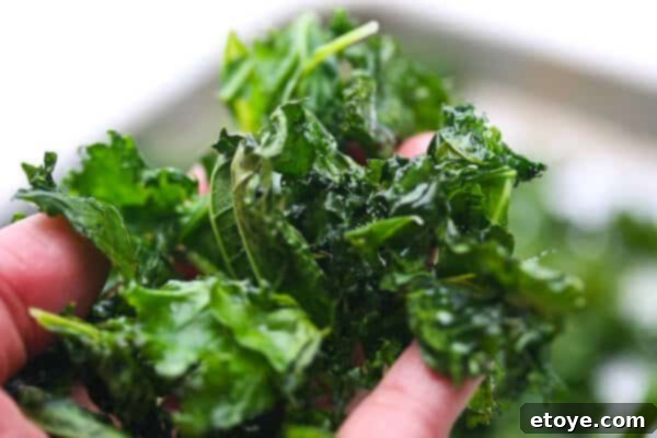Close-up of golden-green crispy kale chips with visible salt crystals