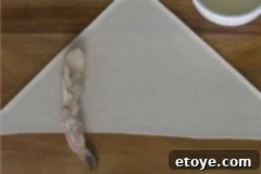 Dynamite Shrimp with Sweet Chili Glaze 3 Step-by-step image of rolling shrimp in a wrapper, showing the tight technique