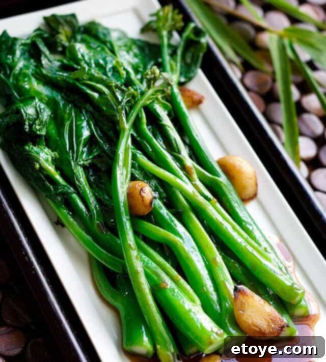 Delicious Chinese Broccoli (Gai Lan) with Oyster Sauce on a white dish, garnished with roasted garlic.