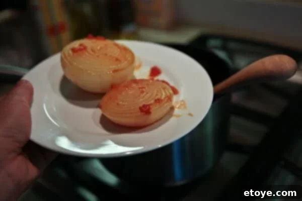 Hand removing the cooked onion from Marcella Hazan's tomato sauce
