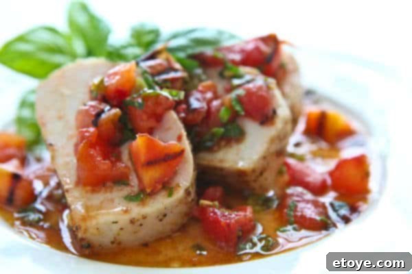 Pork tenderloin slices drizzled with warm grilled tomato salsa, ready to serve.