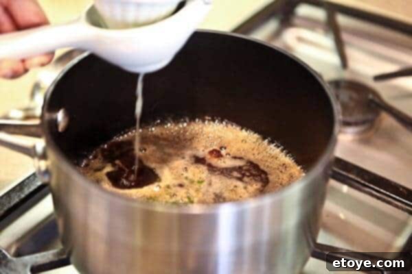 Signature Cola Wings 4 Cola glaze simmering gently in a saucepan, reducing to a thick syrup