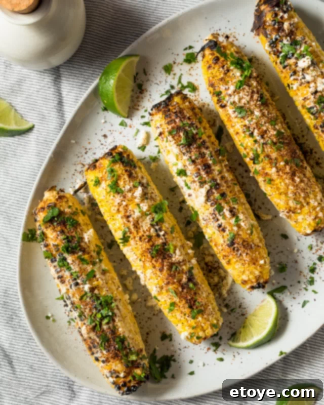 Fourth of July Feast Favorites 4 Four Elote-style corn on the cobs, grilled and garnished with herbs and cotija cheese on a white plate, ready for serving.